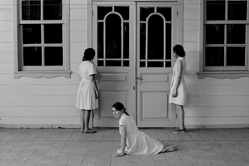 Evdeydim ve Yağmurun Gelmesini Bekliyordum oyunundan üç kadın oyuncunun kapı önündeki siyah-beyaz fotoğrafı